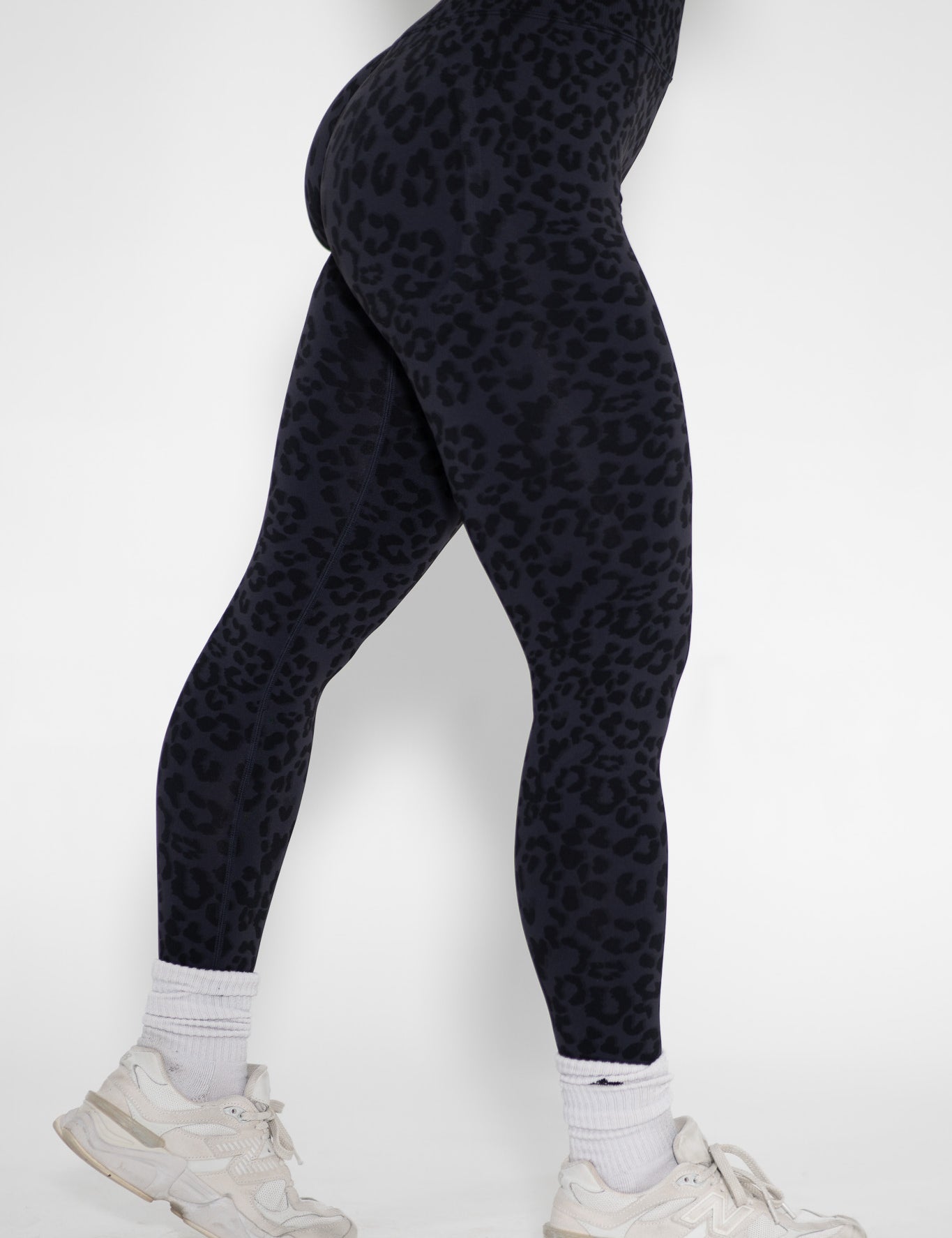 Person wearing black leopard print leggings on a white background