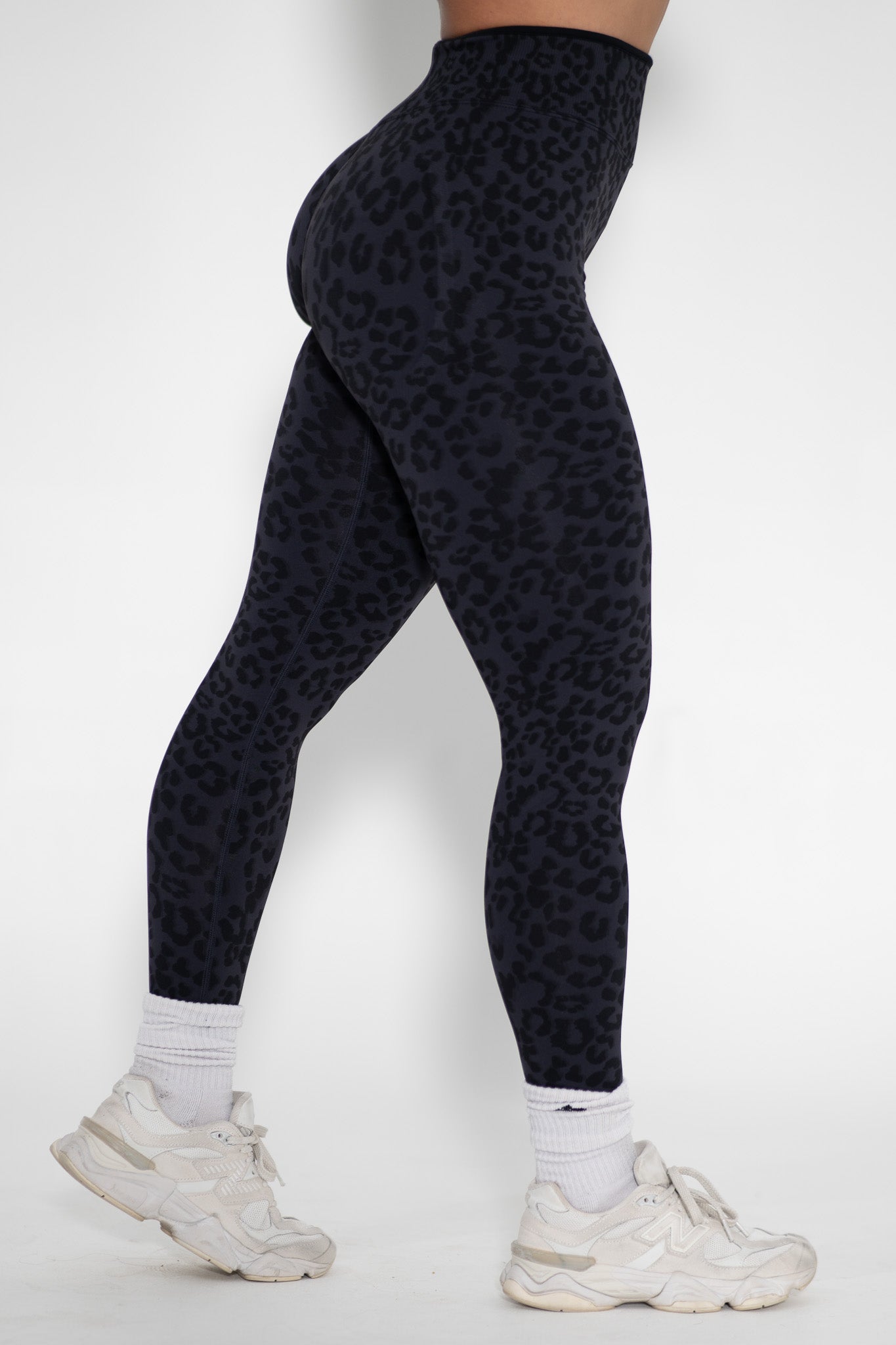 Person wearing black leopard print leggings on a white background
