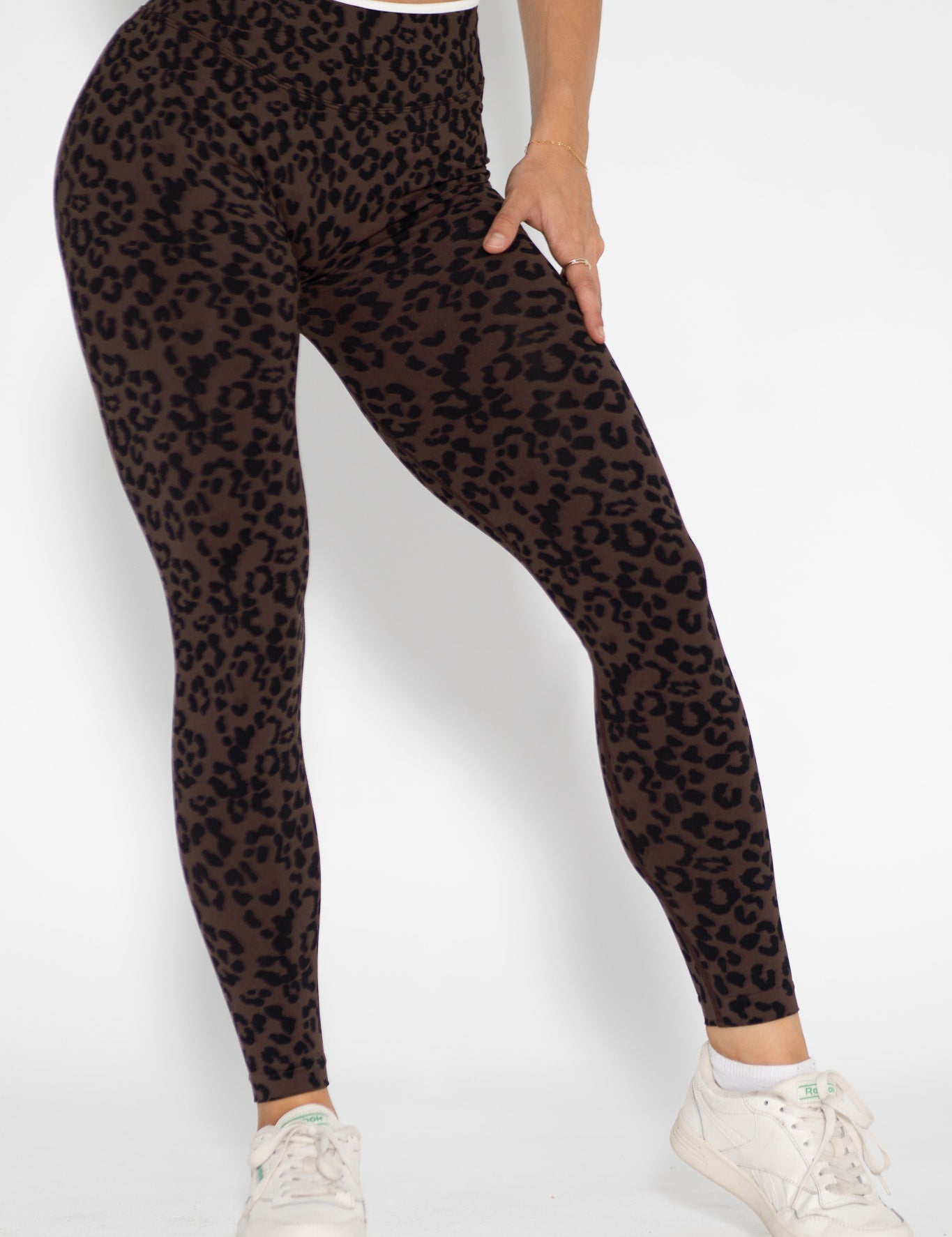 Person wearing leopard print leggings on a white background