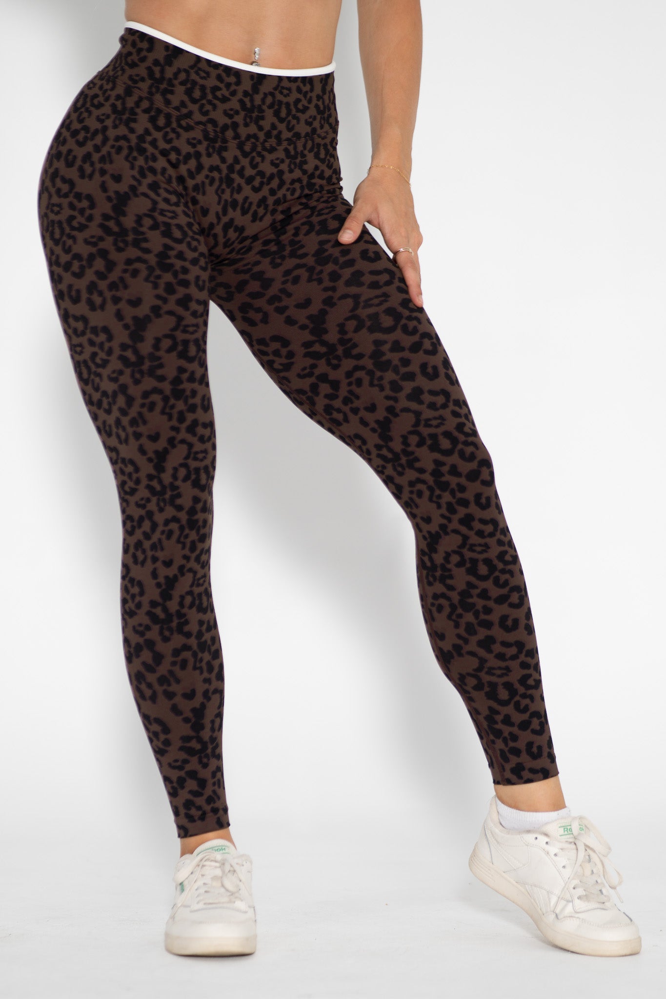 Person wearing leopard print leggings on a white background