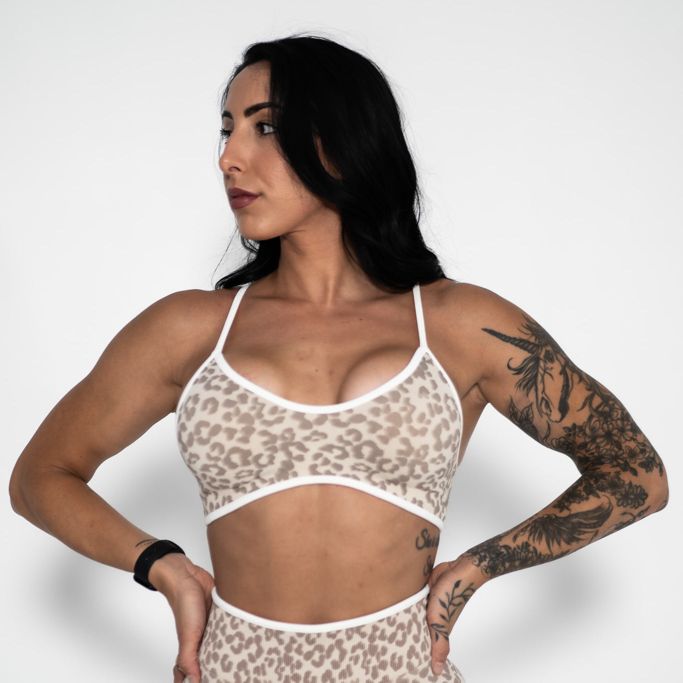 Woman wearing a leopard print sports bra and shorts on a white background