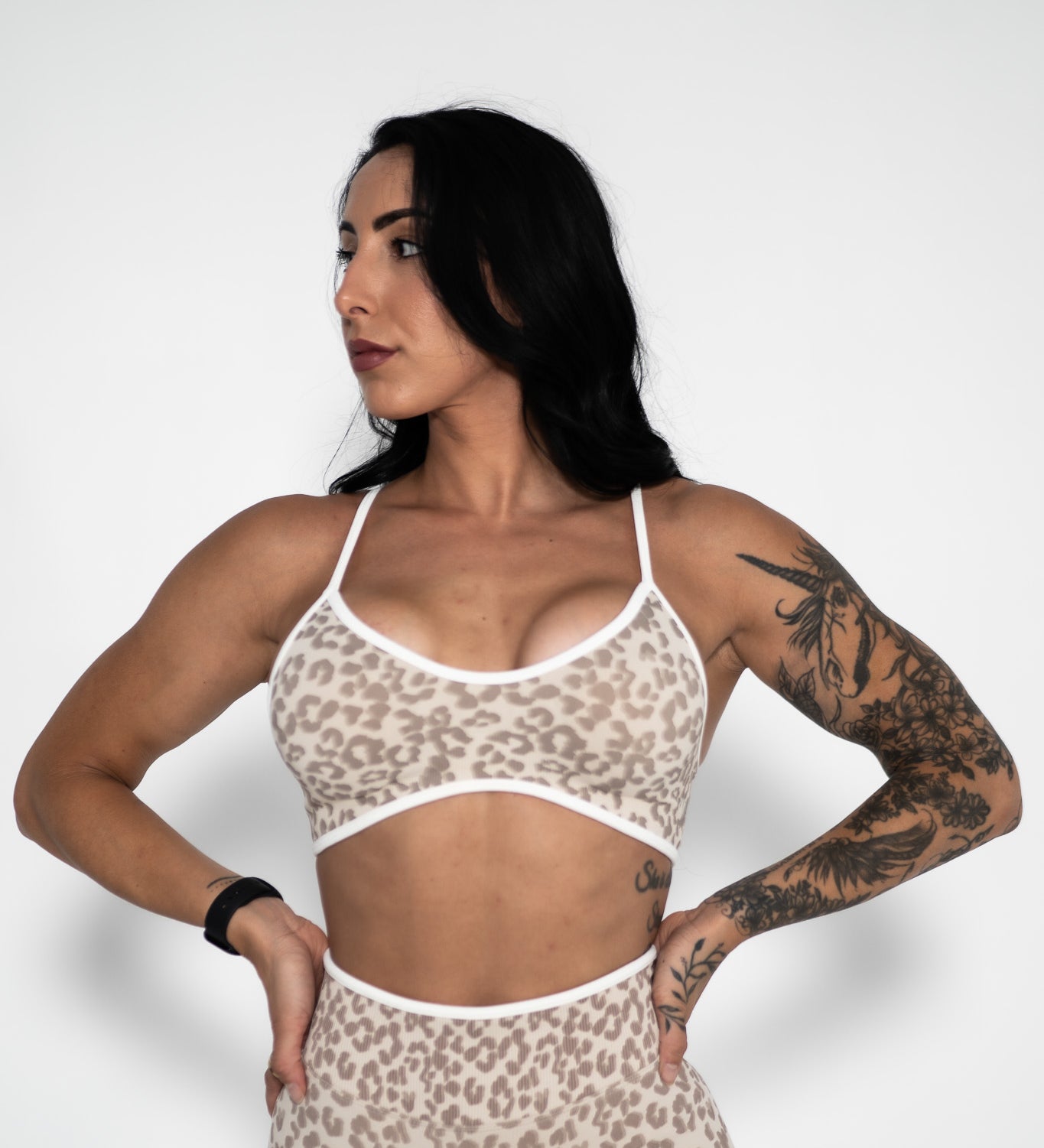 Woman wearing a leopard print sports bra and shorts on a white background