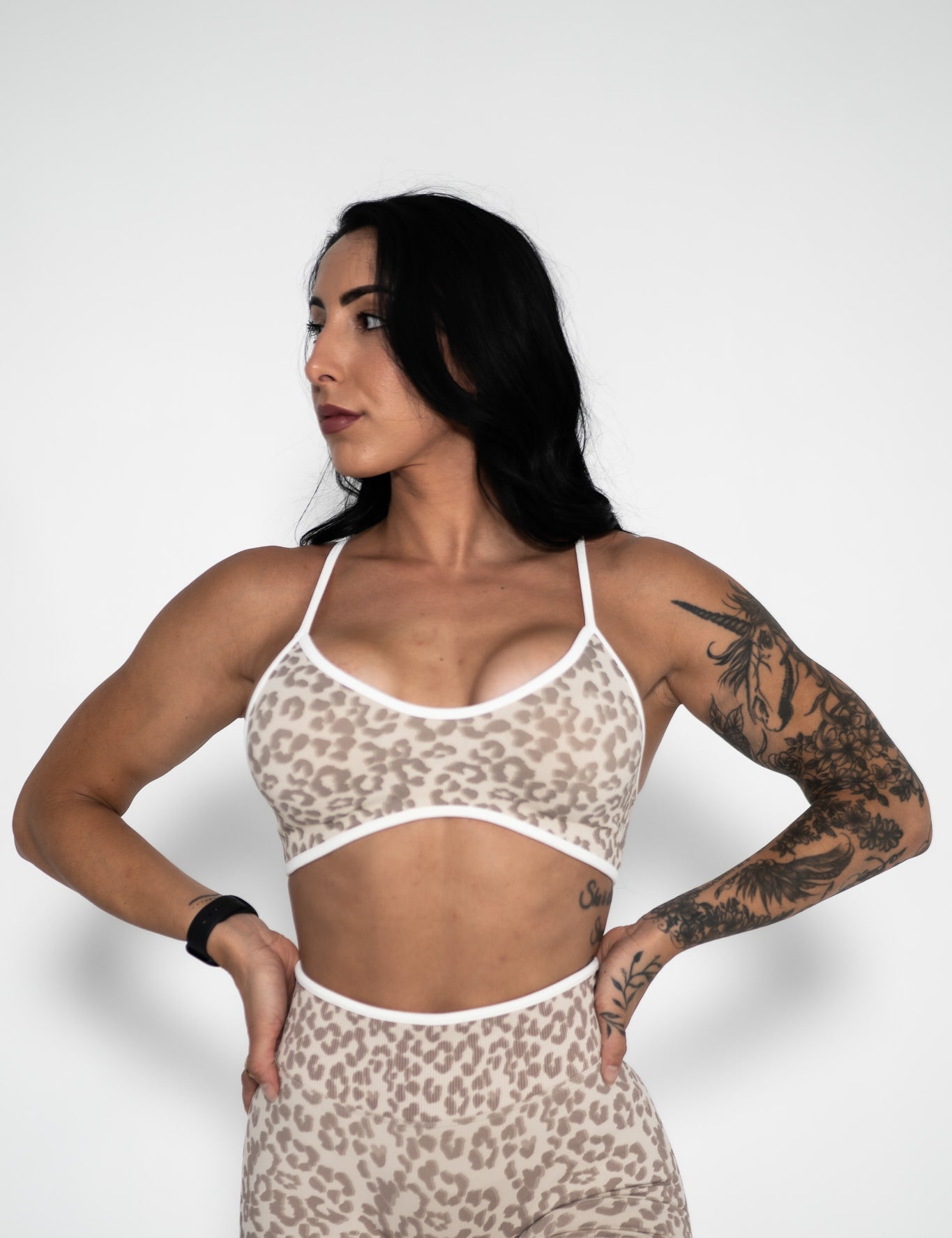 Woman wearing a leopard print sports bra and shorts on a white background