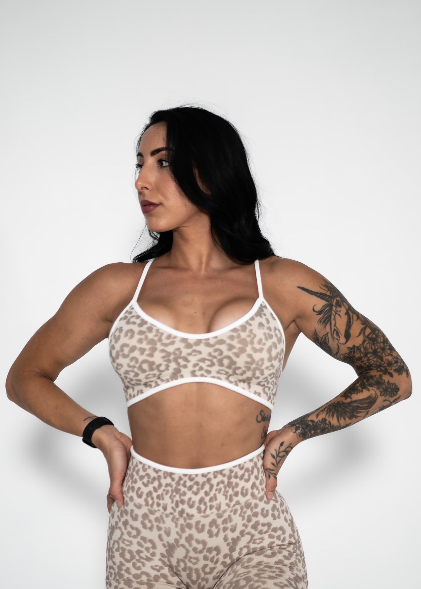 Woman wearing a leopard print sports bra and shorts on a white background