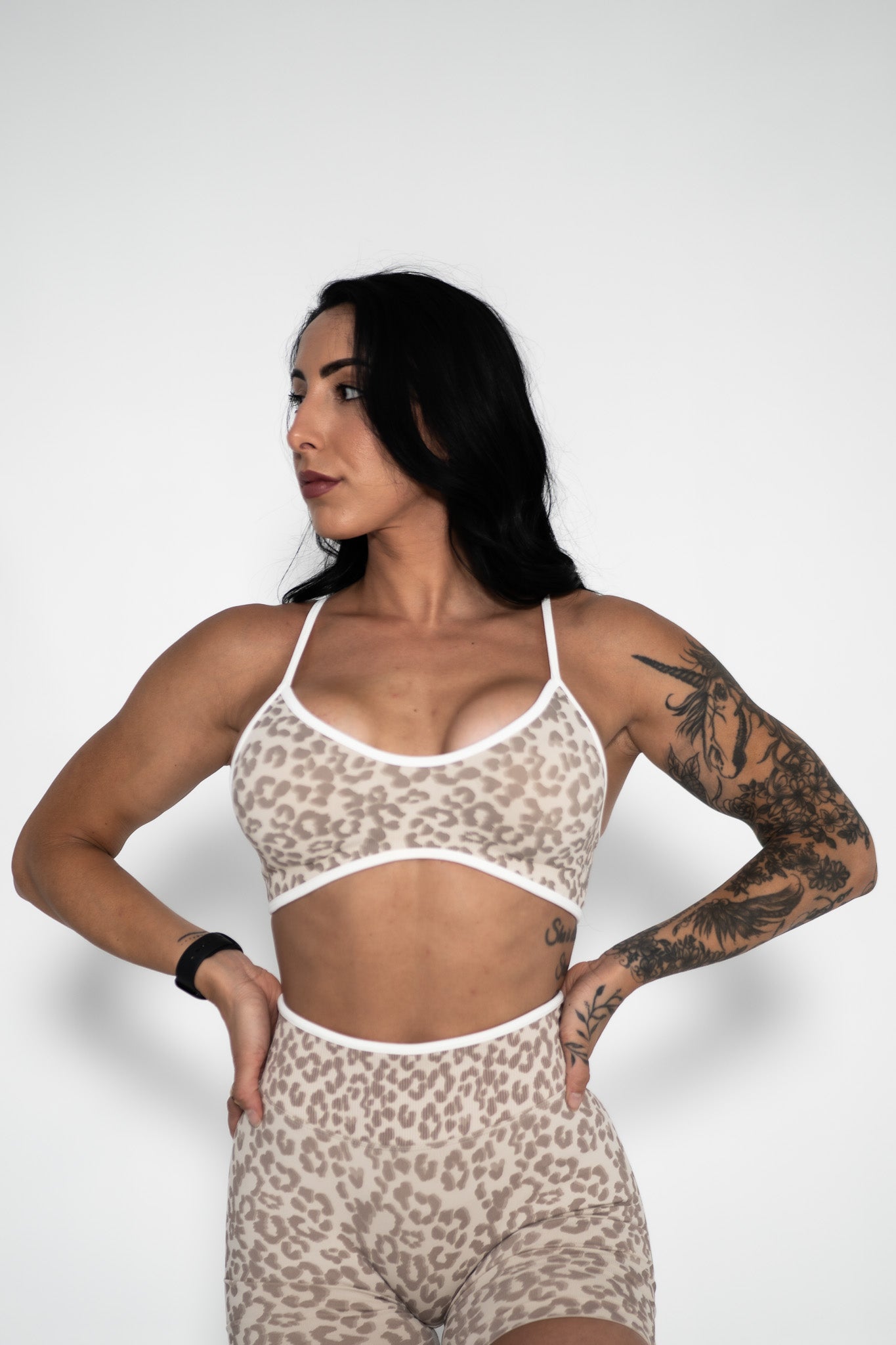 Woman wearing a leopard print sports bra and shorts on a white background