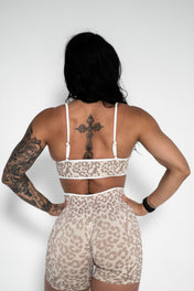 Person wearing a leopard print sports bra and shorts set on a white background