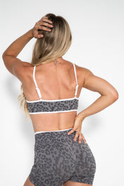 Person wearing a leopard print sports bra and shorts on a white background