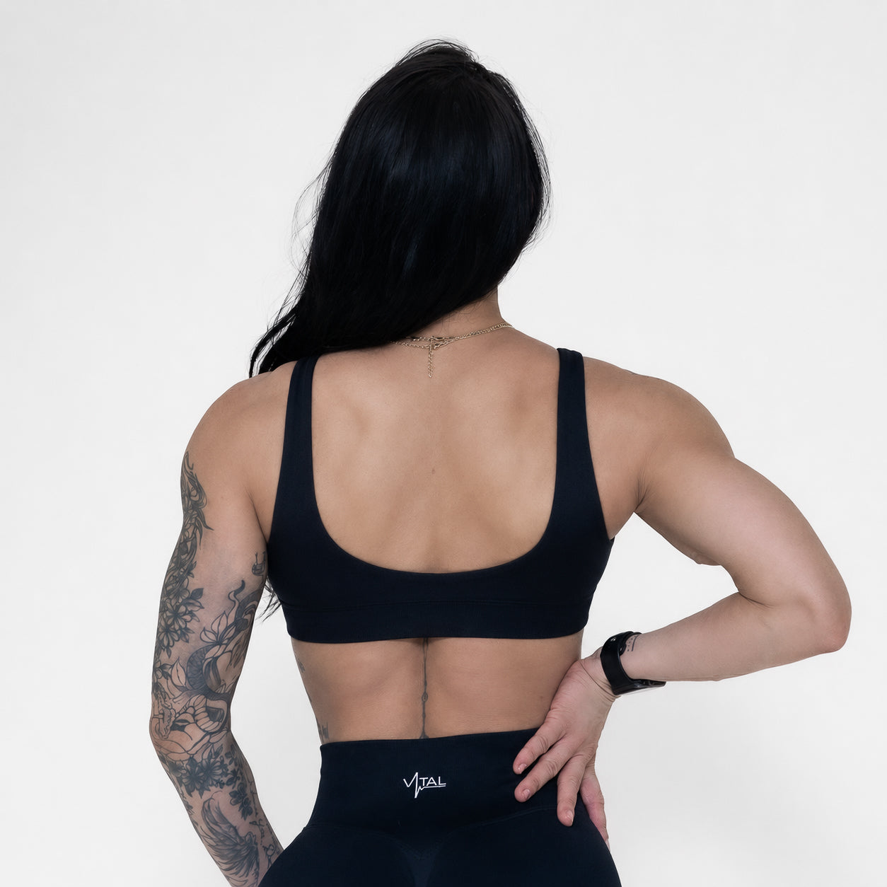 Person wearing a black sports bra and leggings with 'Vital' branding on a white background