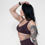 Woman wearing a brown sports bra and leggings against a white background