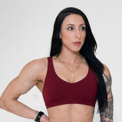 Woman wearing a maroon sports bra against a plain background