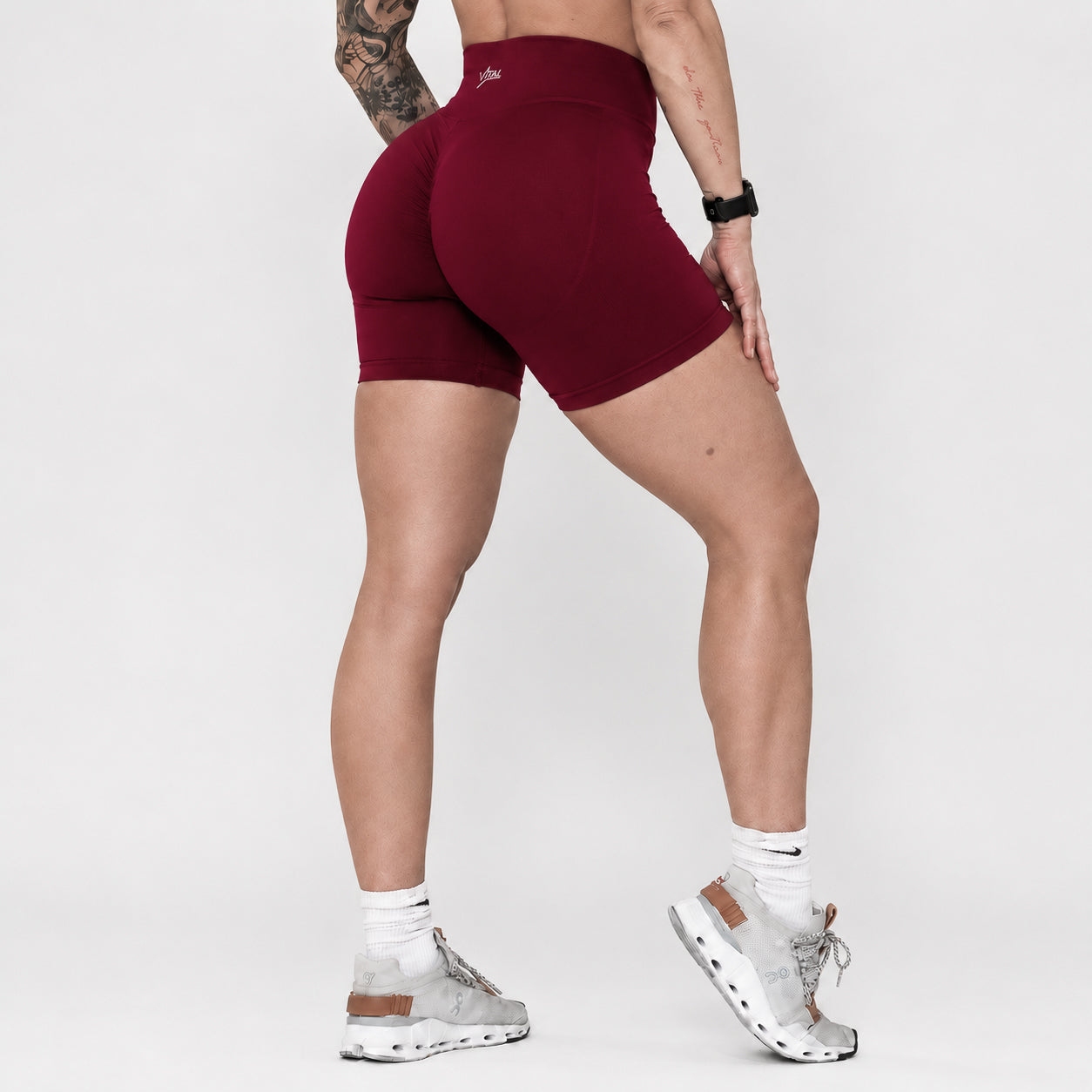 Person wearing maroon athletic shorts on a plain background